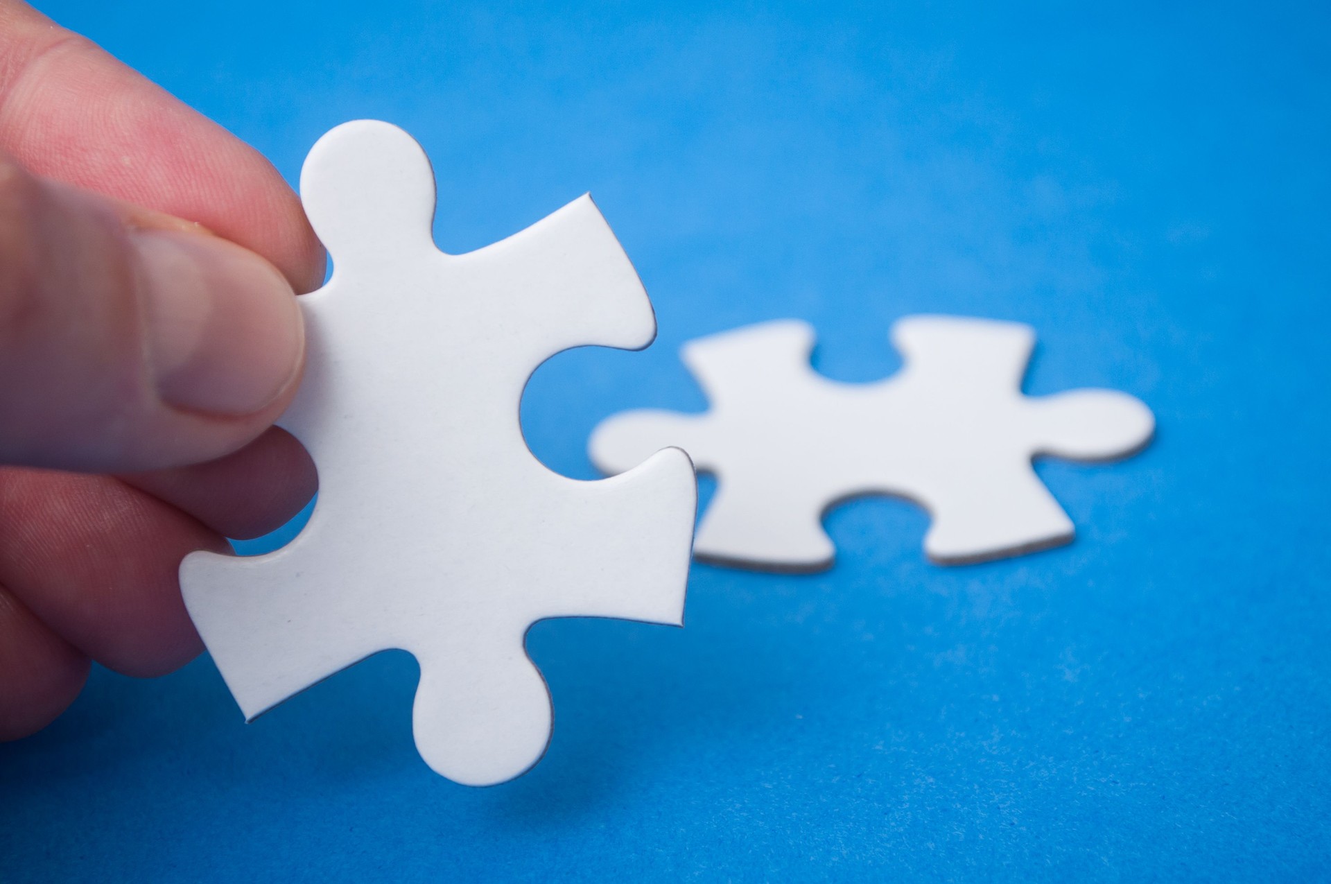 l'homme se connectant avec la main deux pièces de puzzle sur le fond bleu. Le concept de trouver les bonnes solutions dans le travail d'équipe.